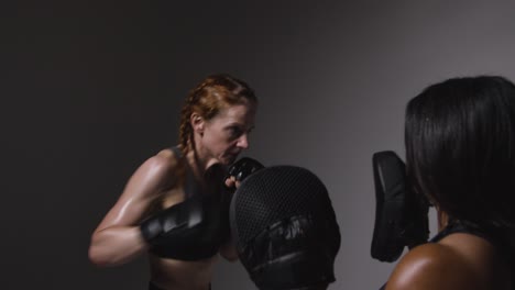 Studio-Shot-Of-Two-Mature-Women-Wearing-Gym-Fitness-Clothing-Exercising-Boxing-And-Sparring-Together